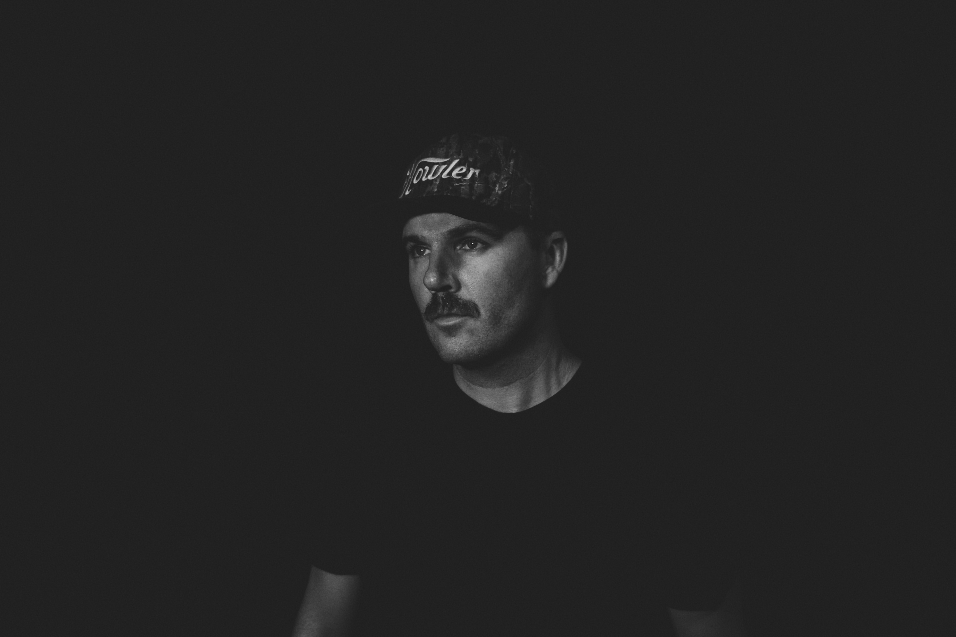 Portrait of Drew Carter wearing a Howler cap, lit against a dark background